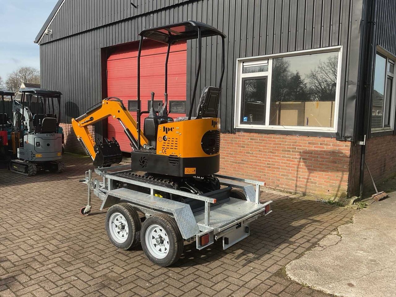 JPC HT-12 mini excavator on trailer, rear three-quarter view JPC HT-12 mini excavator on trailer, rear three-quarter view