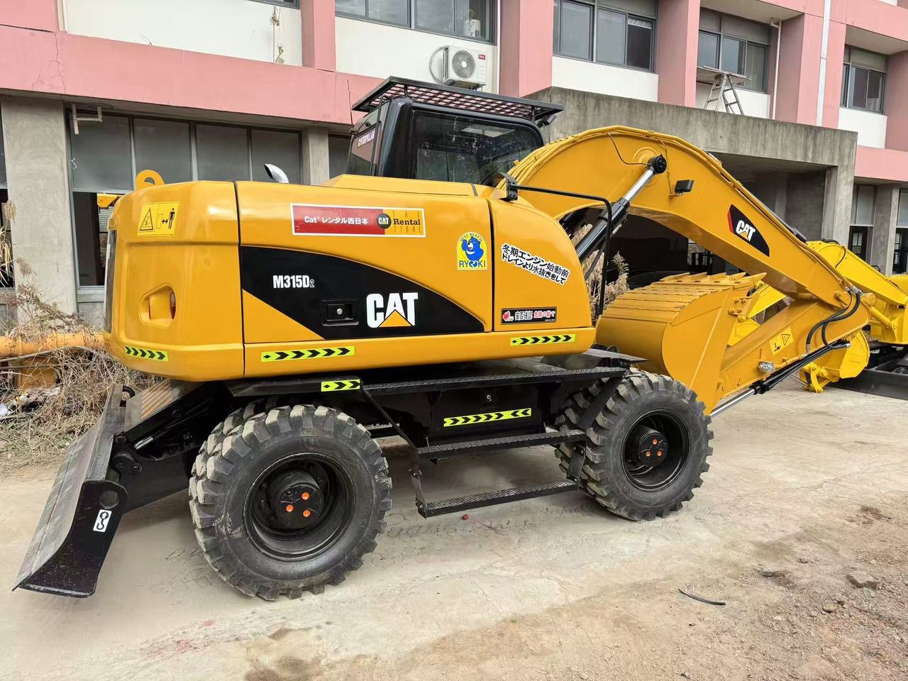 2023 Caterpillar M315D2 wheel excavator, rear three-quarter view 2023 Caterpillar M315D2 wheel excavator, rear three-quarter view