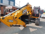 2025 JCB JS200 Crawler Excavator with its bright yellow boom and arm extended forward, showcasing the hydraulic cylinders and black bucket.