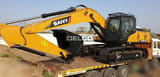 2026 Sany SY240C-9HD Crawler Excavator with a black digging bucket, positioned on the back of a flatbed truck.