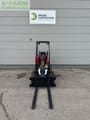 2023 Oehler A6026 Mini excavator with red body and black fork attachment, front view.