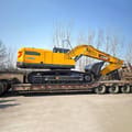 2026 XCMG XE335G Crawler Excavator with its yellow boom and bucket extended over a trailer.