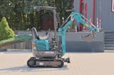 2025 Schmidt AR120 Mini Excavator, side view, highlighting the operator's seat and control levers within the open cab.