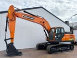 2025 Develon DX205 Crawler Excavator with its orange boom and arm positioned to the side, showing the tracks.
