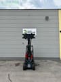 2023 Oehler A6026 Mini excavator with red body and black boom extended vertically, rear view.
