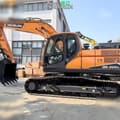 2025 Develon DX225 LC-10 Crawler Excavator with a close-up view of the operator's cab and tracks.