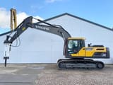 2025 Volvo EC220D Crawler Excavator with a white Maxx 2000 hydraulic hammer attachment on the end of the boom.