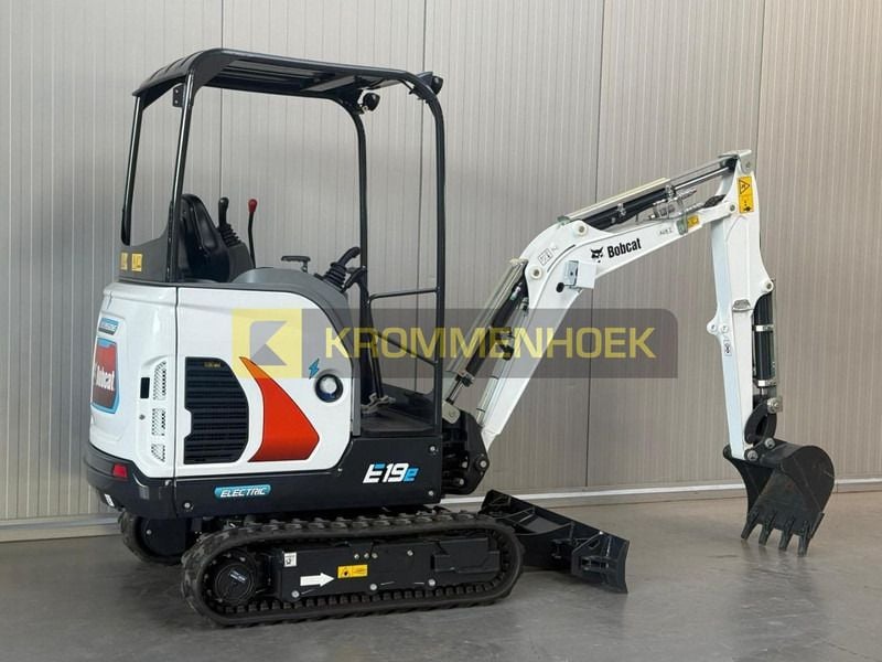 2025 Bobcat E19 Mini Excavator with its white boom and arm positioned to the right, showing the operator station.