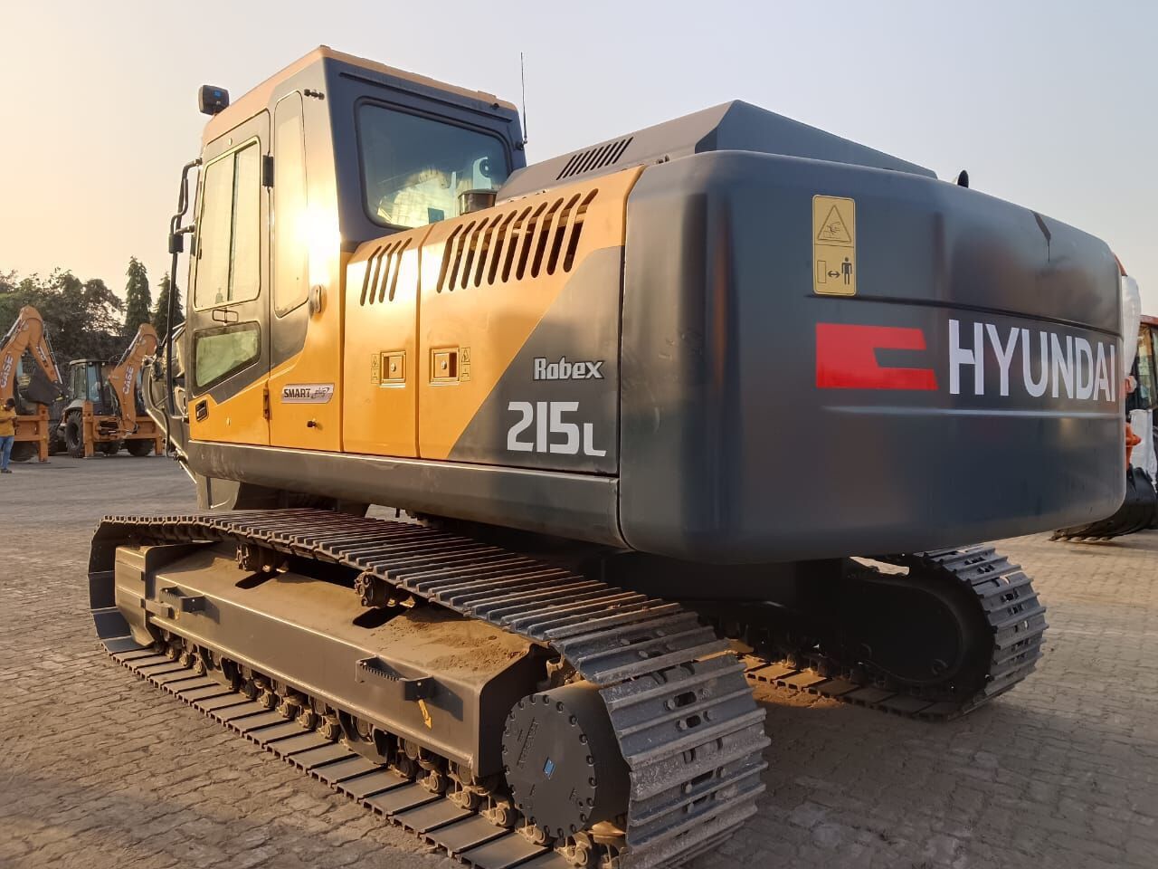 2025 Hyundai R215L Crawler Excavator showing the cab and engine compartment from a side view. 2025 Hyundai R215L Crawler Excavator showing the cab and engine compartment from a side view.
