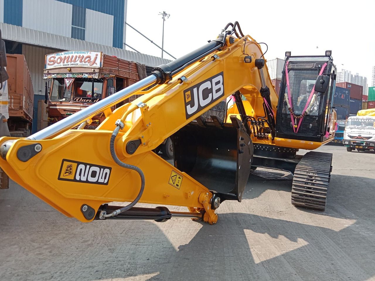 2025 JCB JS200 Crawler Excavator with its bright yellow boom and arm extended forward, showcasing the hydraulic cylinders and black bucket.