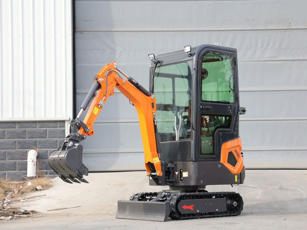 2025 Müller Machinery MB 12-KS H Mini Excavator with orange boom and bucket with teeth, viewed from the front three-quarter angle.