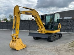 2022 Komatsu PC58-8 Crawler Excavator with its yellow boom and arm extended forward, showing the digging bucket.