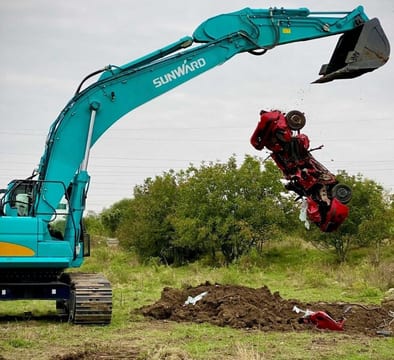 2024 Sunward SWE 335F Mini Excavator with a teal body and a large digging bucket lifting a crushed red car. 2024 Sunward SWE 335F Mini Excavator with a teal body and a large digging bucket lifting a crushed red car.